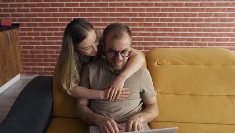 freelancer besando la mejilla de una mujer alegre cerca de la computadora portátil