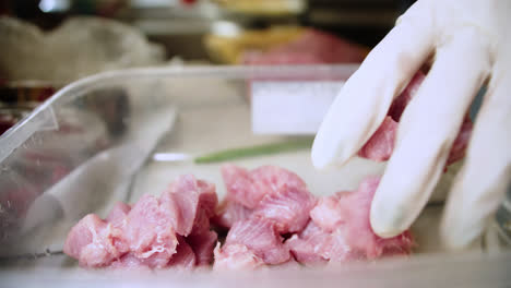 placing raw fish pieces in a glass container after cutting them