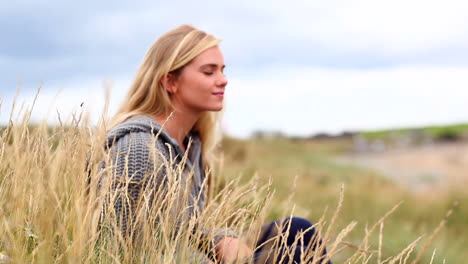 una mujer rubia relajándose en las dunas.