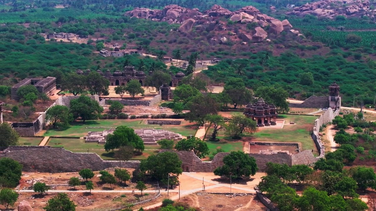 Lotus Mahal con Recinto Zenana, Stagno della Regina, torri di guardia e Stalle degli Elefanti a Kamalapura, Hampi, Vijayanagara, Karnataka, India. Di giorno, carrellata, ripresa con drone, 4K.
