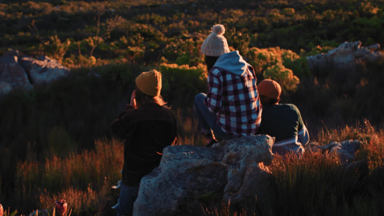한 무리의 친구들이 함께 술을 마시며 아름다운 시골에서 휴식을 취하며 일몰을 즐기고 있습니다.