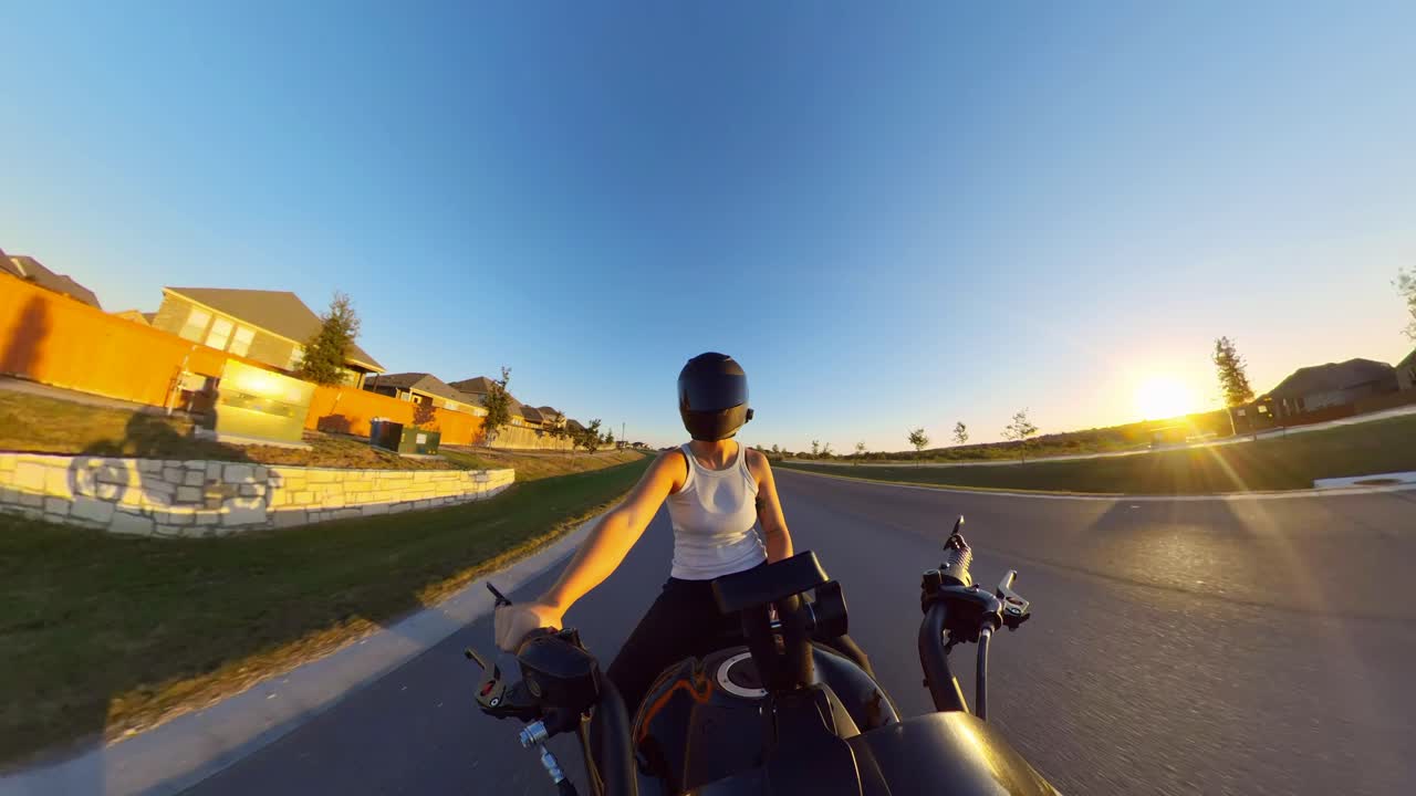 Motorcyclist cruising through quiet streets at sunset, neighborhood bathed in golden light