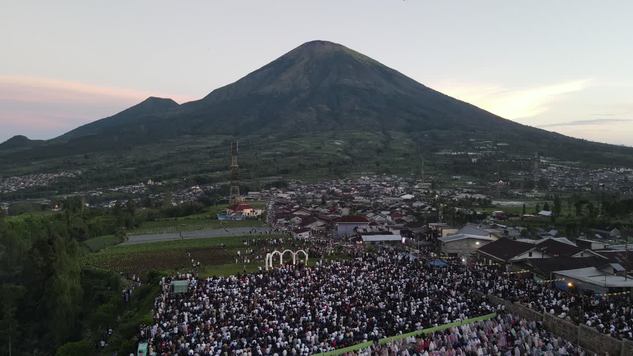 Aerial view, thousands of worshipers praying Eid al-Adha or Eid al-Fitr in Garung Village, Wonosobo. Praying with the most beautiful view of Mount Sumbing and Sindoro.