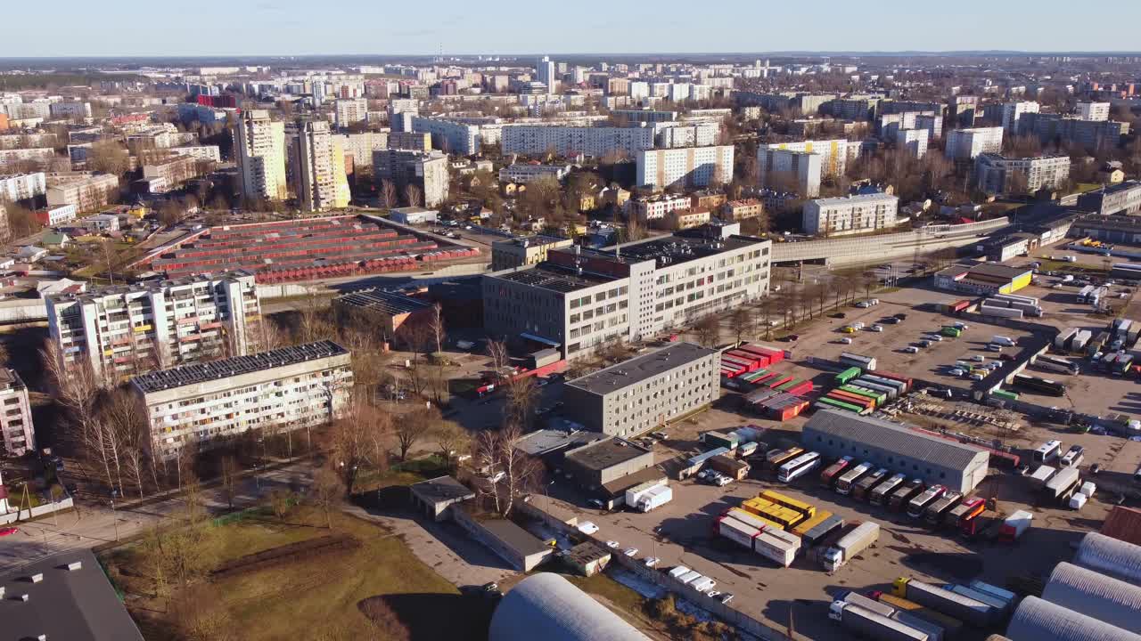 Aerial drone view of industrial area with trucks, containers, warehouses and apartment buildings. Eastern European city from above.