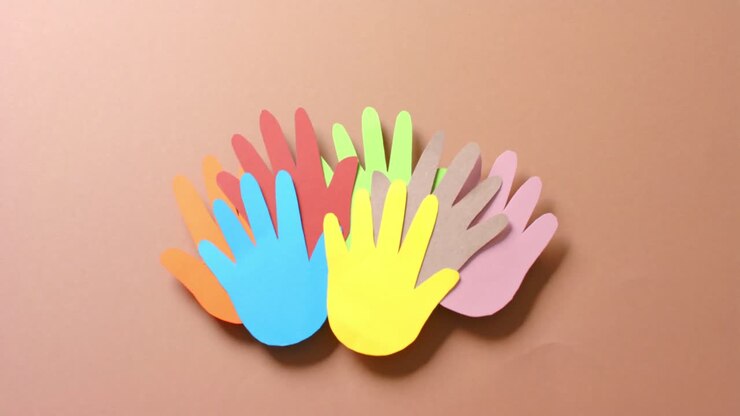 Close up of hands together made of colourful paper on brown background with copy space