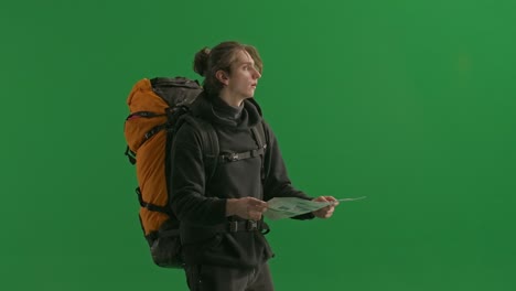 man with backpack reading a map on green screen