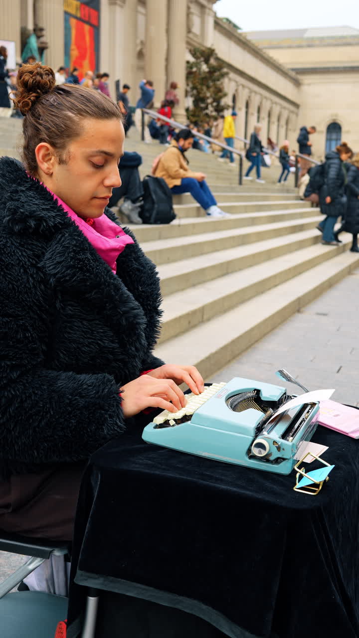 New York, USA, 2 March 2026: Street poet writing on typewriter at museum entrance. A writer in a black coat using a vintage typewriter on a table at the Metropolitan Museum of Art stairs