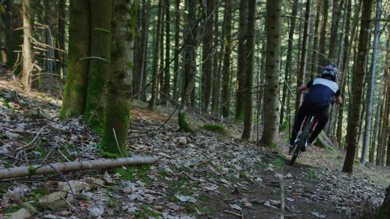 un ciclista de montaña levanta una rama mientras monta en su rueda trasera en cámara lenta