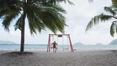 Turista-Masculino-Disfrutando-De-Un-Columpio-En-Una-Playa-De-Hai-En-La-Isla-De-Con-Dao,-Vietnam