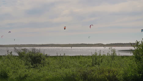 kitesurfers sailing with the wind at floras lake in oregon - wide shot, slow motion