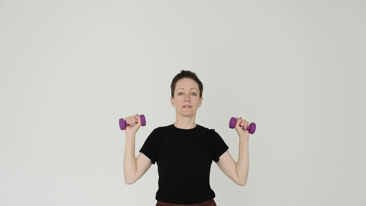 Woman performing exercises with dumbbells on white background