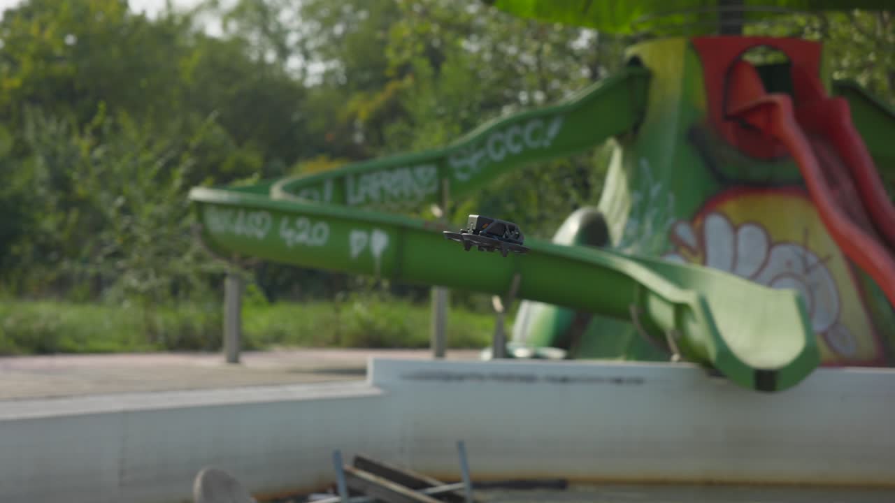 el dron dji avata vuela entre las toboganes en un patio de recreo al aire libre abandonado