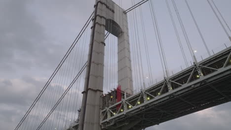 drone point of view looking up at the verrazano-narrows bridge. shot at dusk in brooklyn