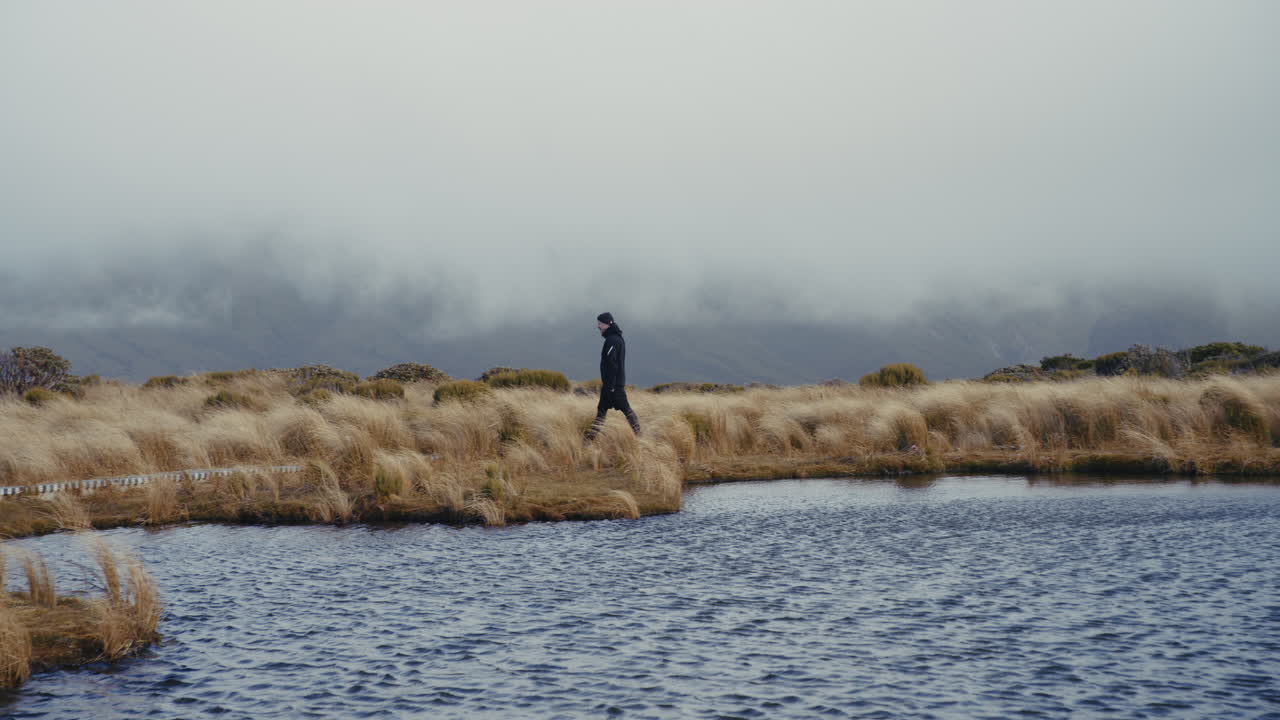 Escursionista a un lago di montagna con nebbia