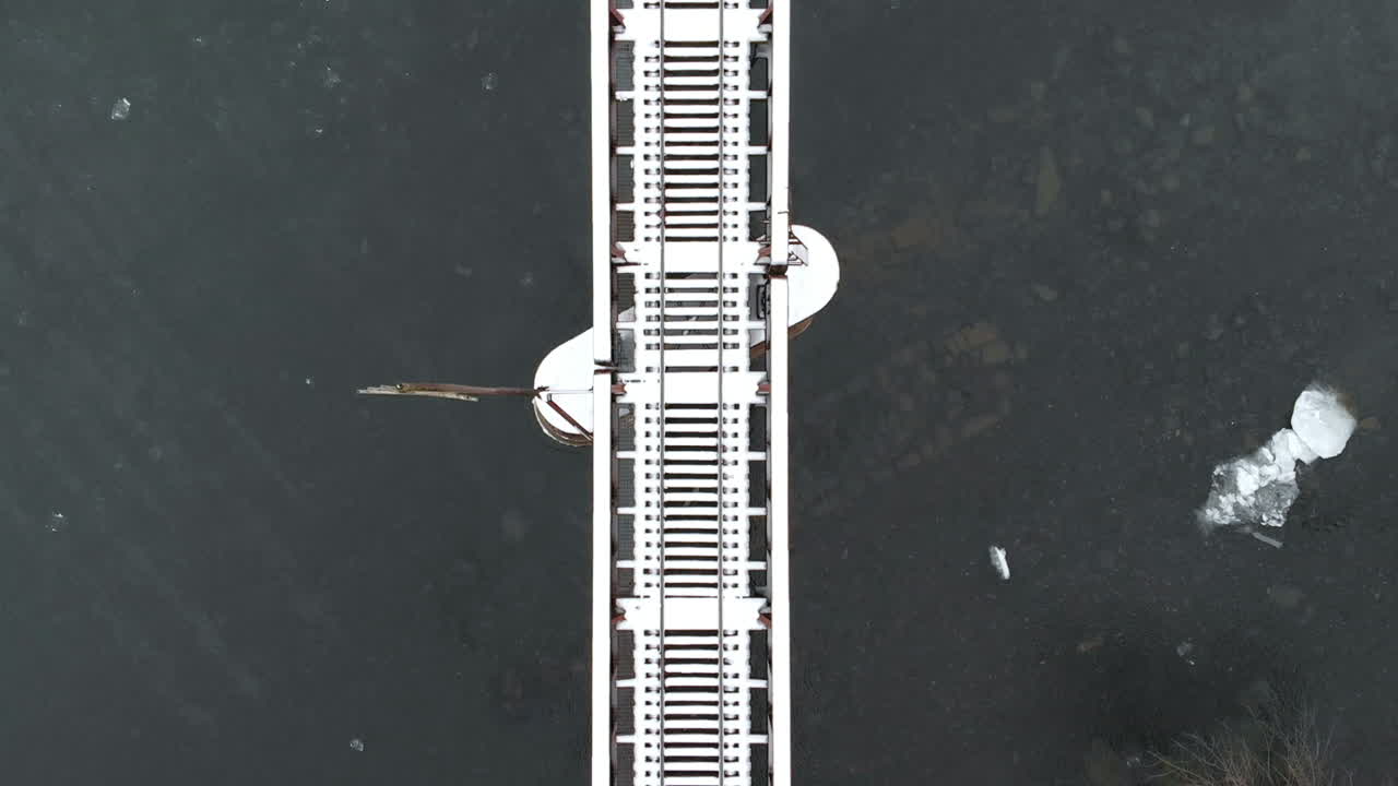 заснеженный железнодорожный мост через ледяную реку воздушный широкий полет вниз замедленная съемка