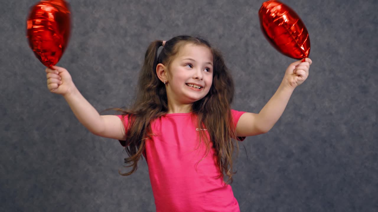 Retrato de niña linda con globos. Retrato de niña pequeña linda sosteniendo globos en forma de corazón