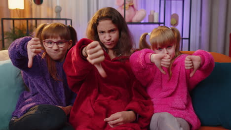 three girls on a couch giving thumbs down