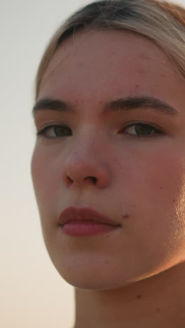 primer plano de una joven con expresión de mal humor mirando directamente a la cámara bajo la cálida luz del sol, transmitiendo emociones profundas, efecto bokeh suave de la vegetación en el fondo