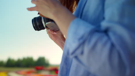 Closeup-woman-hands-holding-professional-photo-camera-in-blooming-garden-outdoor