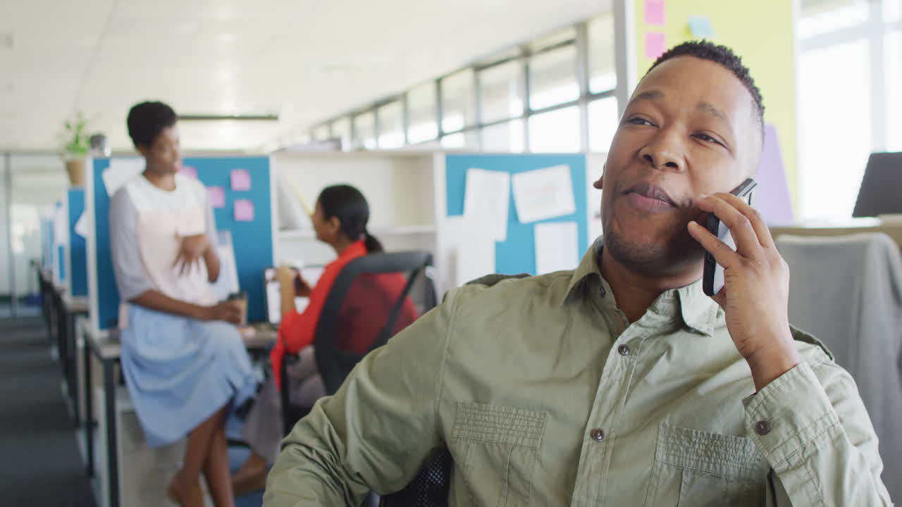 African american businessman talking on smartphone at office, slow motion
