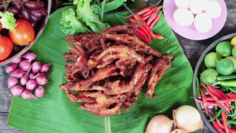 top down view fried chicken feet displayed on banana leaf, table full of vegetables