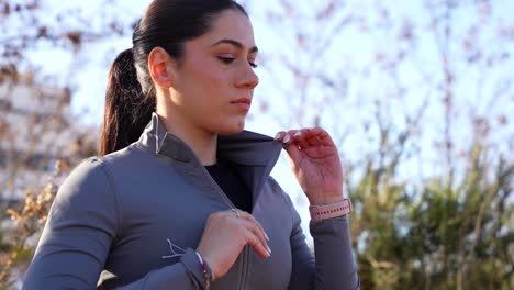 mujer al aire libre abriendo una chaqueta, atrapando el aliento y sintiéndose cansada después del ejercicio