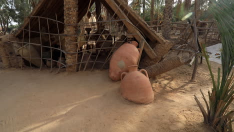 traditional african huts with thatched roofs and large pottery in a dusty village setting, daytime