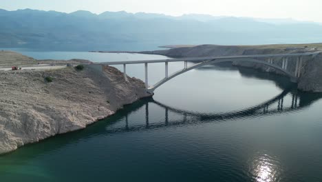 un giro aéreo desde la isla pag sobre el puente con la cordillera velebit en el sitio y luego hacia la fortaleza de fortica y el faro de luz