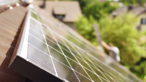 Closeup-of-installed-solar-panel-on-roof,-blurred-worker-climbing-ladder