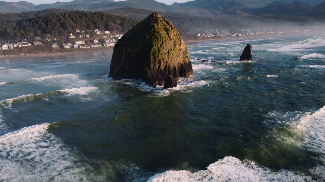 Imagens de drone costeiras mostrando litoral rochoso, montanhas e ondas do oceano em Cannon Beach. Ideal para mídias de atividades ao ar livre e viagens.