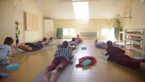 Yoga-students-on-bellies-lift-chest-and-legs-off-floor-in-core-and-back-exercise