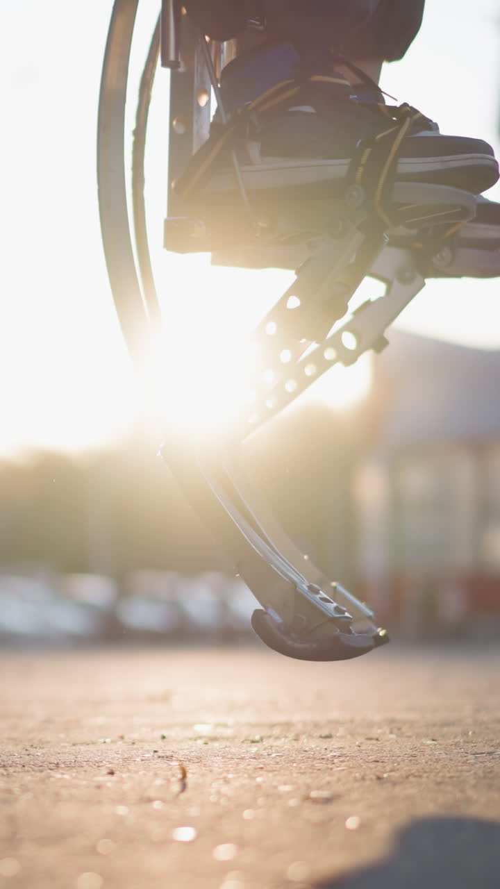 Close-up of modern prosthetic limb with metallic spring design jumping in outdoor setting under bright sunlight. The background features a blurred green park, suggesting energy and activity
