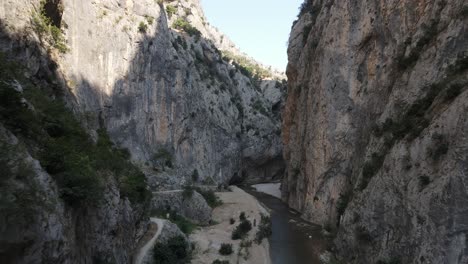 Drohnenaufnahme-Der-Riesigen-Schlucht,-Die-Sich-Zwischen-Zwei-Großen-Bergen-Gebildet-Hat,-Blick-Auf-Den-Fluss,-Der-Durch-Die-Schlucht-Fließt