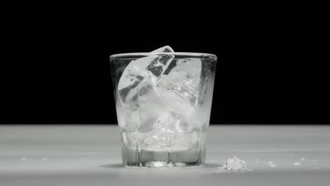 hand quickly pouring ice cubes into a glass cup