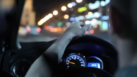 el conductor pone la mano en el volante del coche. carretera nocturna y aspectos destacados de los coches que pasan. primer plano. vista desde el asiento trasero. 4k cámara lenta