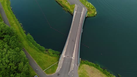 도르니 호수 (dorney lake) 에서 트라이애슬론을 하는 트라이아슬론 선수들이 자전거를 타고 트랙에서 경쟁하며 물 다리를 건너고 있습니다.