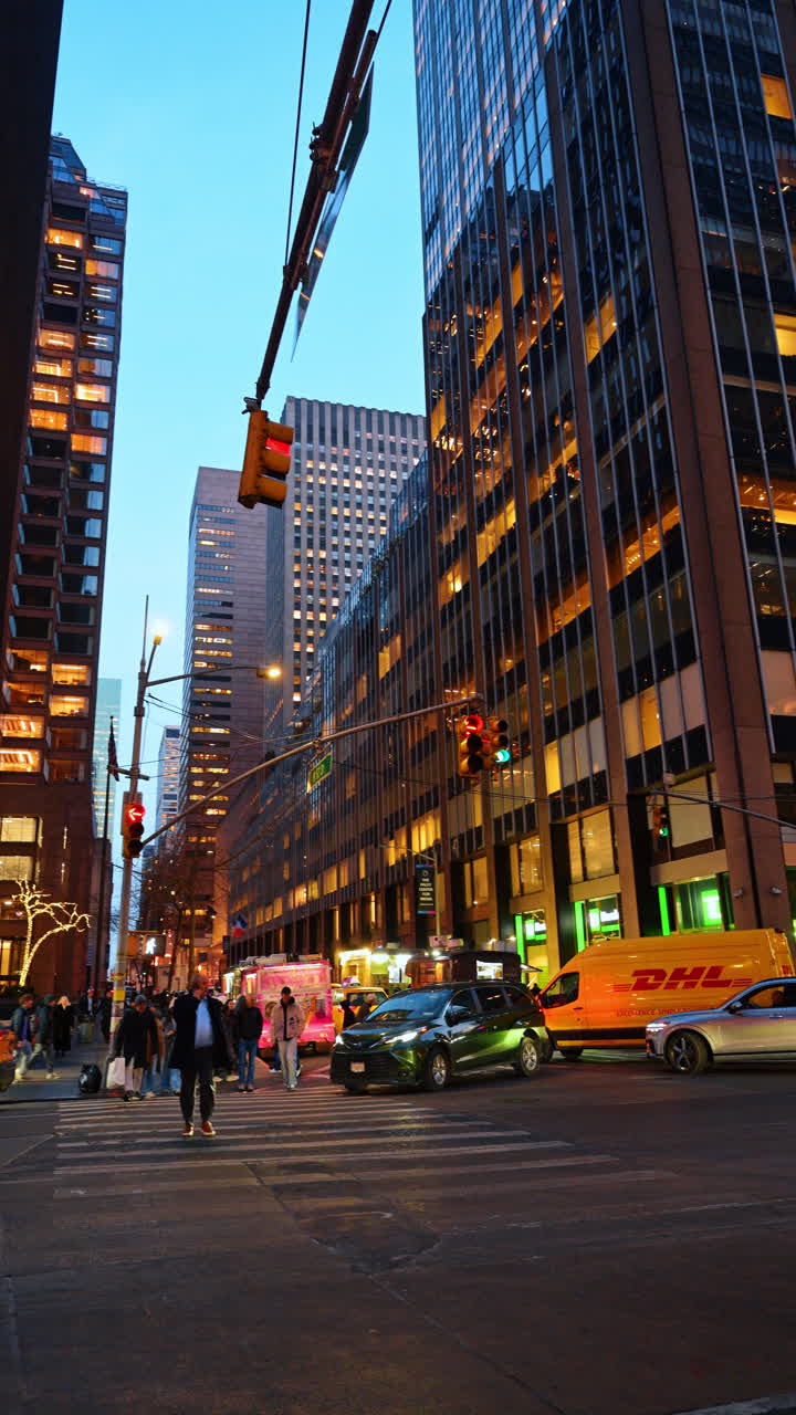 New York, USA, 24 dicembre 2025: strada di Manhattan di sera con traffico. Intersezione trafficata di Manhattan al crepuscolo con pedoni e traffico circondati da grattacieli illuminati.