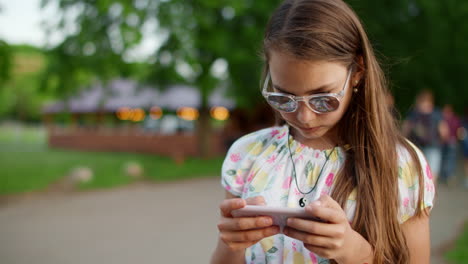 concentrated teen girl looking smartphone. serious girl reading news in mobile