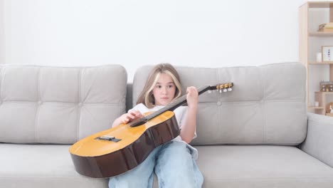 a child learns to play a small guitar. art is a genuine hobby.