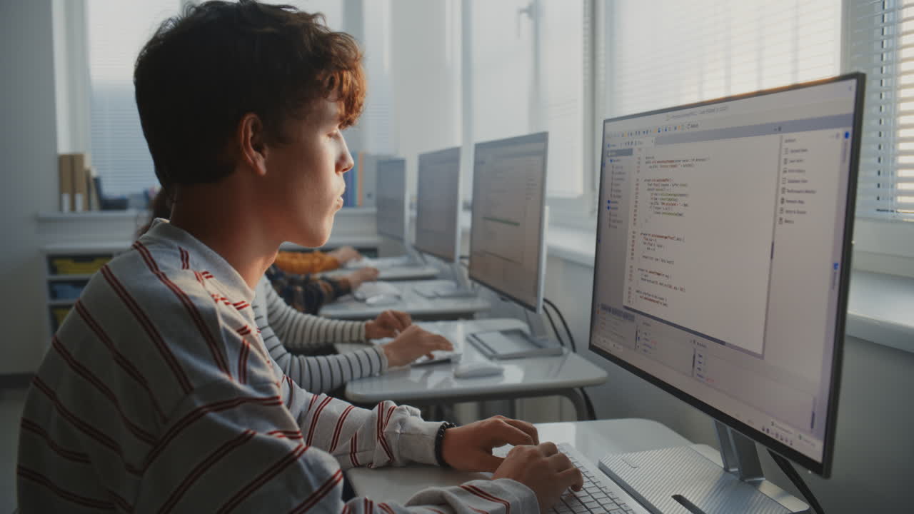 University Students Sit at Computers in Well Lit Classroom Opposite Window Writing Program Code