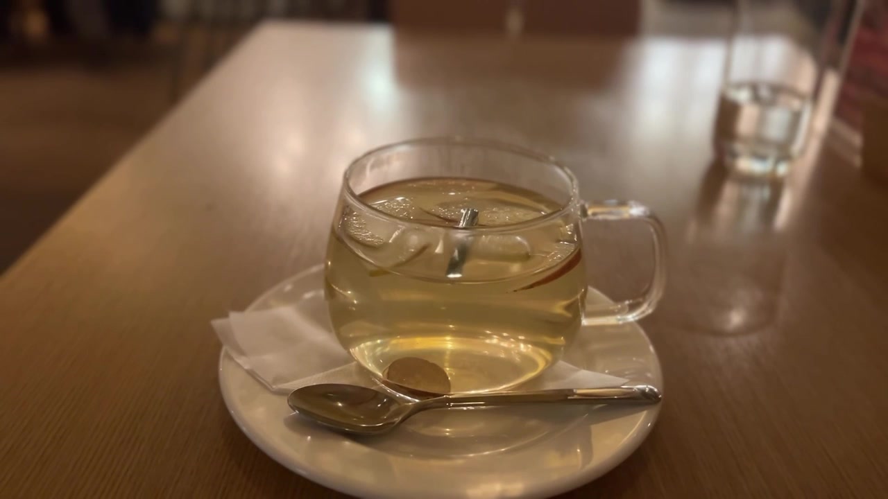 Tazza di vetro con tè caldo e limpido alla mela e cannella.