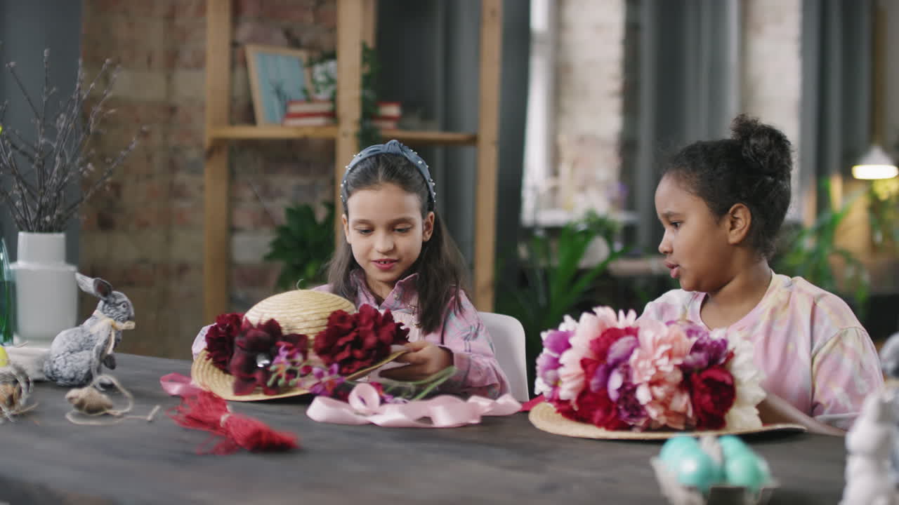 Kleine Mädchen verzieren Sonnenhüte mit Blumen