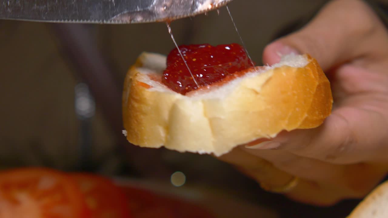 Preparing a strawberry jam sandwich