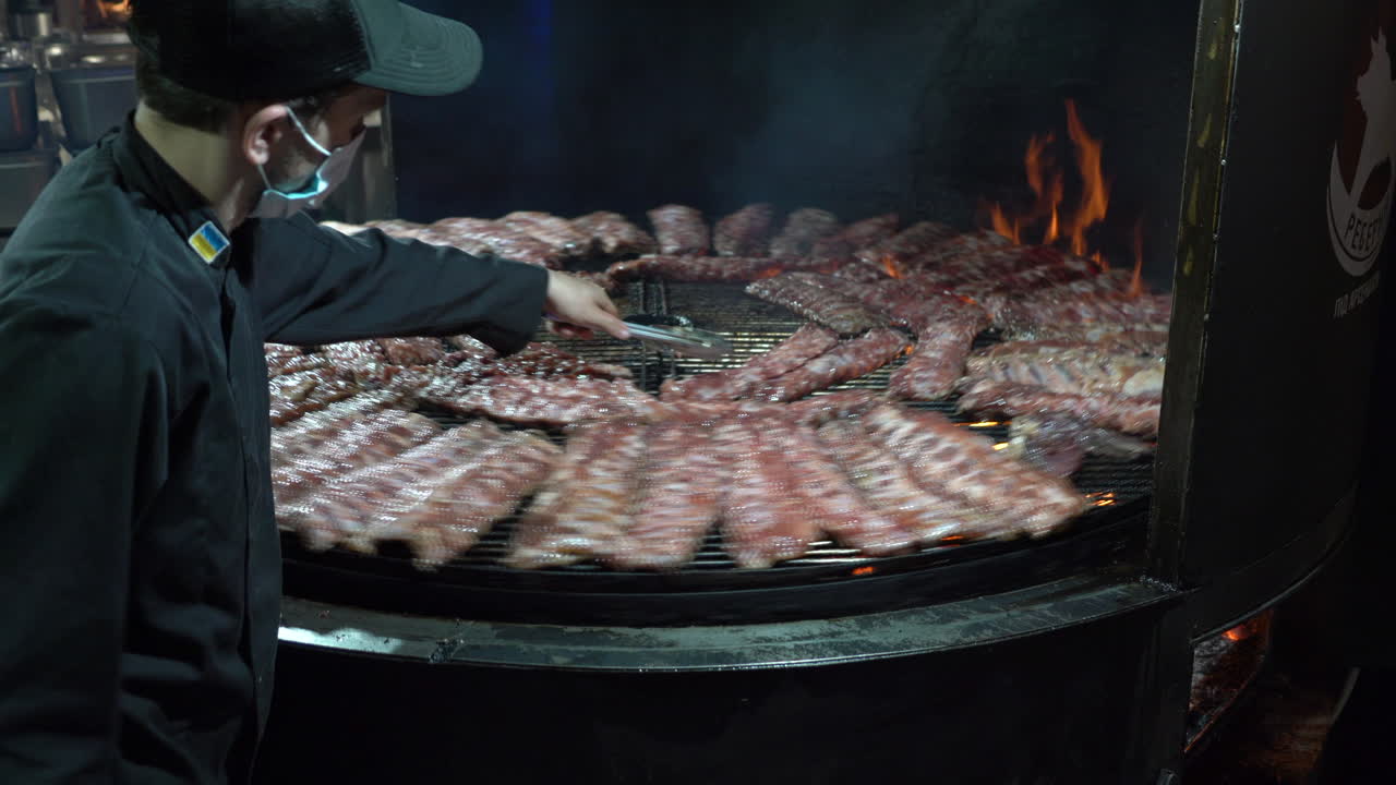Chef Grilling a Large Quantity of Ribs on a Rotating Grill