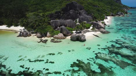 vista aérea de una mujer en kayak en la playa de seychelles con rocas y agua turquesa