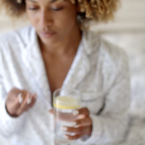 mujer tomando pastillas en la cama