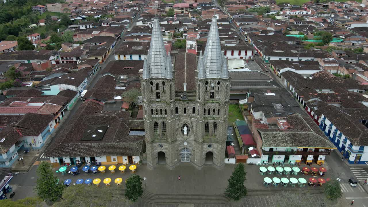 Aerial establishing front of Jardin’s Basilica of the Immaculate Conception central plaza, colonial architecture and vibrant local culture in Colombia