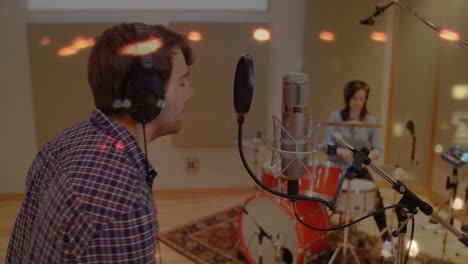 male vocalist and drummer performing recording session, showing microphone icon and audio waveforms