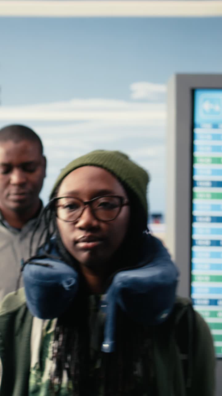 Vertikal video: Gruppe af turister og forretningsrejsende går rundt i lufthavnsterminalen.