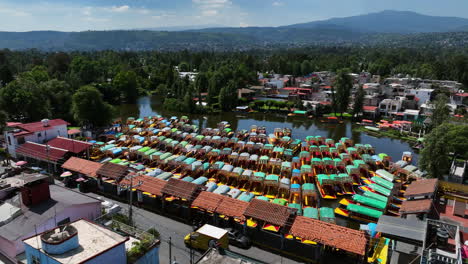 drone diving over trajinera boats docked at the xochimilco lake, in mexico